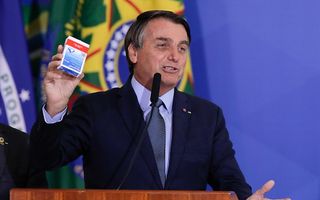 De Braziliaanse president Bolsonaro met een pakje hydroxychloroquine, september dit jaar. beeld AFP, Sergio Lima