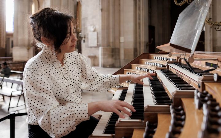Een vrouw speelt op een orgel met vijf klavieren 