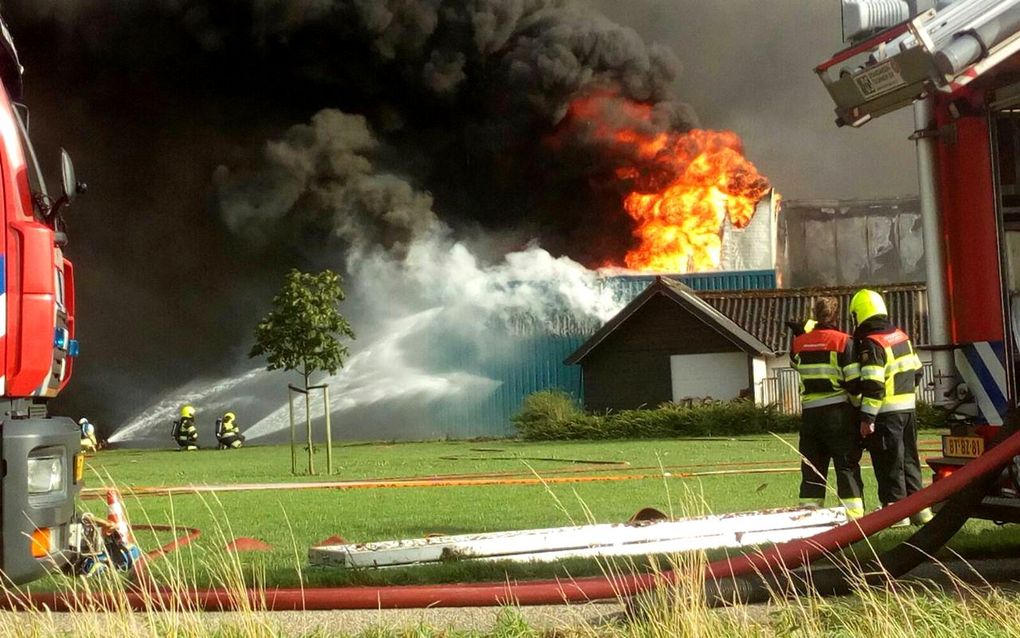 De brandweer bestrijdt het vuur in een varkensstal bij Erichem. beeld ANP