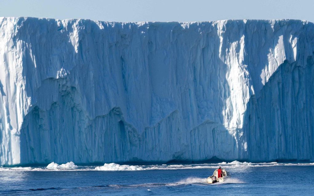 Een boot voor een ijsberg in Disko Bay, Ilulissat, West-Groenland. De berg ijs is afkomstig van de Jakobshavn-gletsjer (Sermeq Kujalleq), de meest productieve gletsjer van op het noordelijk halfrond. De ijsmassa's die van de gletsjer loskomen, drijven jarenlang in het water voor de fjord voordat ze door oceaanstromingen naar het zuiden worden gevoerd. beeld AFP, Odd ANDERSEN