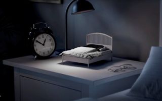 Een miniatuurbedje met een smartphone erop staat op een nachtkastje.