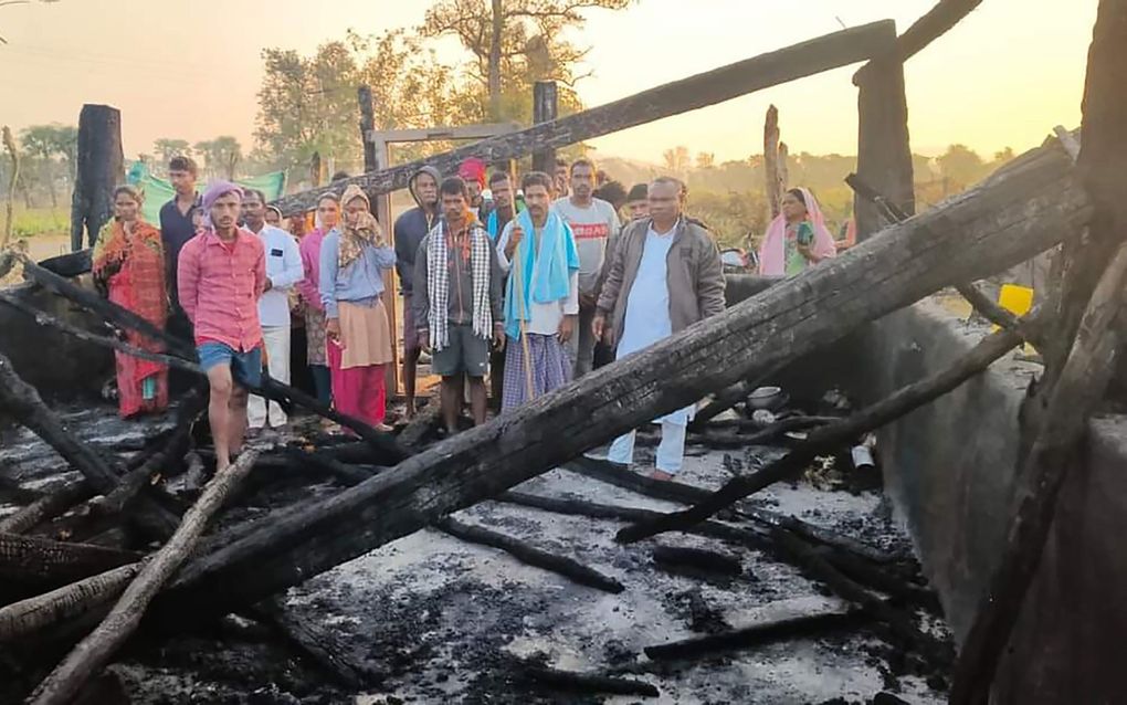 Indiase christenen tussen de verkoolde resten van hun kerkgebouw. beeld HVC