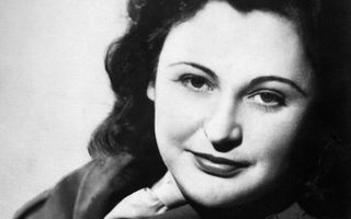 Zwart-wit foto van een jonge vrouw met donker krullend haar gekleed in uniformjas.