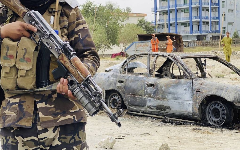 Een talibanstrijder houdt de wacht bij een auto die werd gebruikt om raketten af ​​te vuren op de luchthaven in Kabul. beeld EPA, Stringer