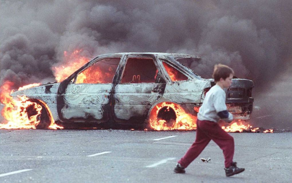 Een jongen rent in 1996 tijdens The Troubles voor een brandende auto in de rooms-katholieke wijk Shortstrand in Belfast. beeld AFP, Gerry Penny