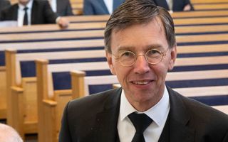 Predikant met bril in zwart pak.