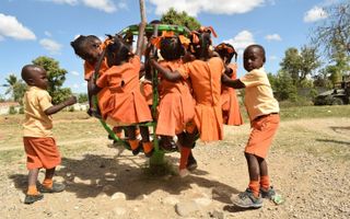 In het oranje geklede schoolkinderen spelen buiten.