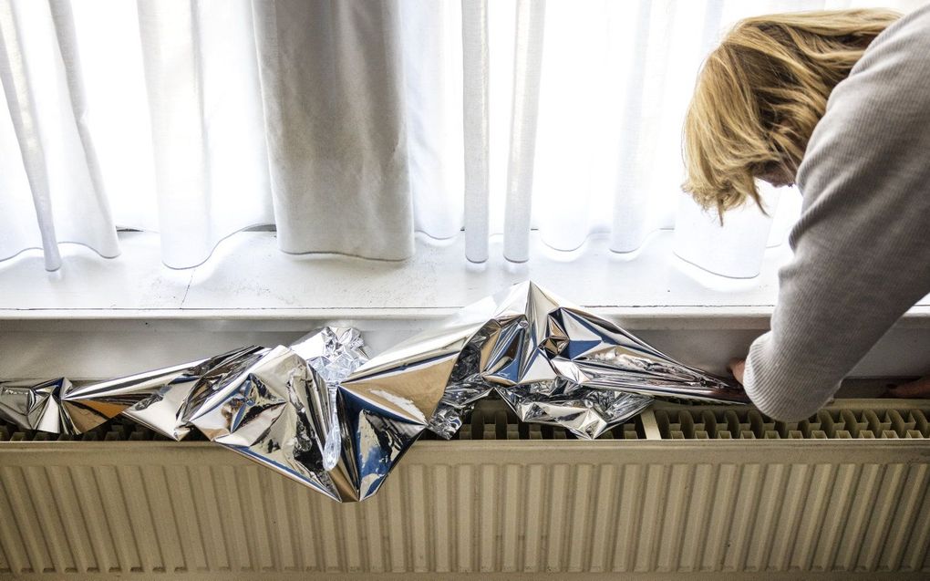 Het plaatsen van radiatorfolie bij een radiator om energie te besparen. beeld ANP, Ramon van Flymen