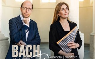 Een man en een vrouw staan voor een witte pilaar in een kerk. De vrouw heeft een panfluit in haar handen.