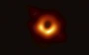Zwarte gaten zijn onzichtbaar, relatief klein, maar enorm zwaar. De foto laat laat een gloeiende ‘donut’ van stof en sterren zien, met daarbinnen de schaduw van een zwart gat. Het zwarte gat is nog eens 2,5 keer kleiner dan zijn schaduw. beeld EHT Collabo