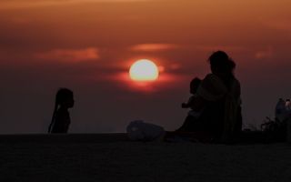 Mensen verzamelen zich tijdens zonsondergang op Ajman Beach, in de Verenigde Arabische Emiraten. beeld EPA, Ali Haider