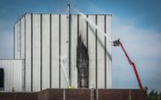 De brandweer blust een grote brand bij de voormalige kerncentrale Dodewaard. Er is geen risico op het vrijkomen van radioactieve straling door de brand. beeld ANP