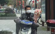 Valentijnsrozen kopen met een mondkapje op, in Hangzhou, China. beeld AFP