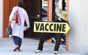 Een man met mondmasker wijst de weg naar een vaccinatielocatie in de Amerikaanse stad Los Angeles. In de VS groeit het verzet tegen allerlei vormen van vaccinatiedrang, vooral onder Republikeinen. beeld AFP, Frederic J. Brown