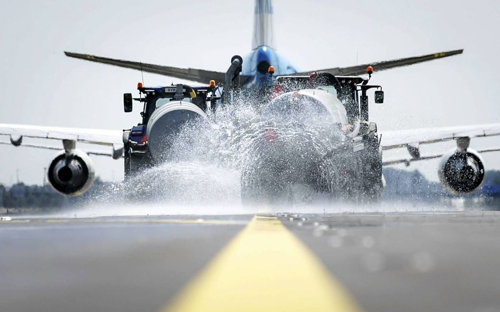 Op de taxibanen van Schiphol werden donderdag sproeiers aangezet om vervorming van het asfalt te voorkomen. Het kan op de banen 50 graden worden, waardoor het asfalt begint te smelten. beeld Robin van Lonkhuijsen