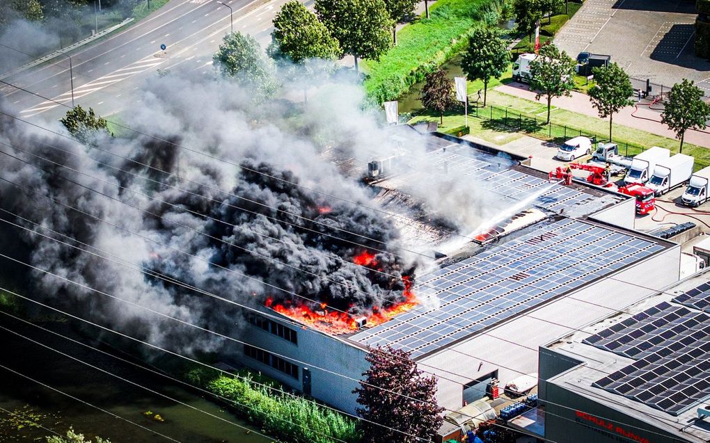 Vlammen slaan uit het dak en zwarte rook komt vrij bij een grote brand in het bedrijfspand in Alblasserdam. beeld ANP,  JEFFREY GROENEWEG