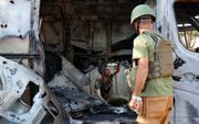 Israëlische strijdkrachten onderzoeken een verwoest voertuig. beeld AFP, JACK GUEZ 