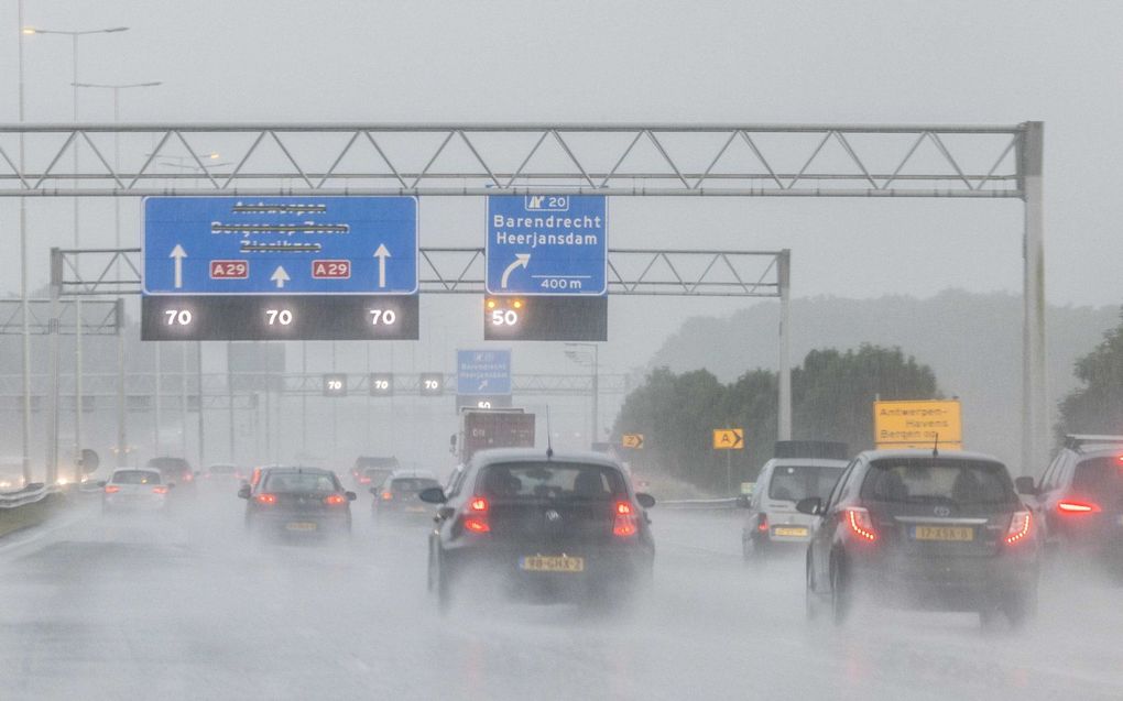 Auto's rijden langzaam op de snelweg bij Rotterdam door hevige regenval. beeld ANP, JEFFREY GROENEWEG