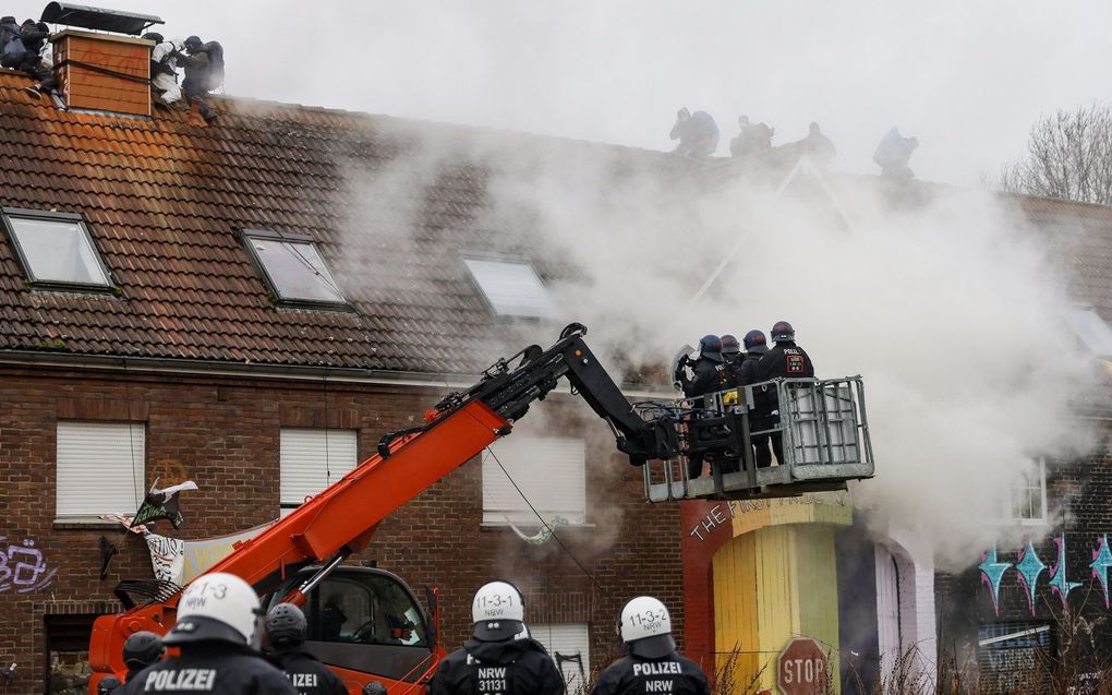 Politieagenten betreden een van de bezette huizen in het dorp Lützerath. beeld EPA, RONALD WITTEK