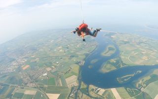 Skydive-instructeur Leander van der Snel op een tandemsprong met fotograaf Niek Stam, zwevend boven Walcheren. Goed te zien zijn Arnemuiden, Middelburg en het Veerse Meer. beeld Skydive Zeeland