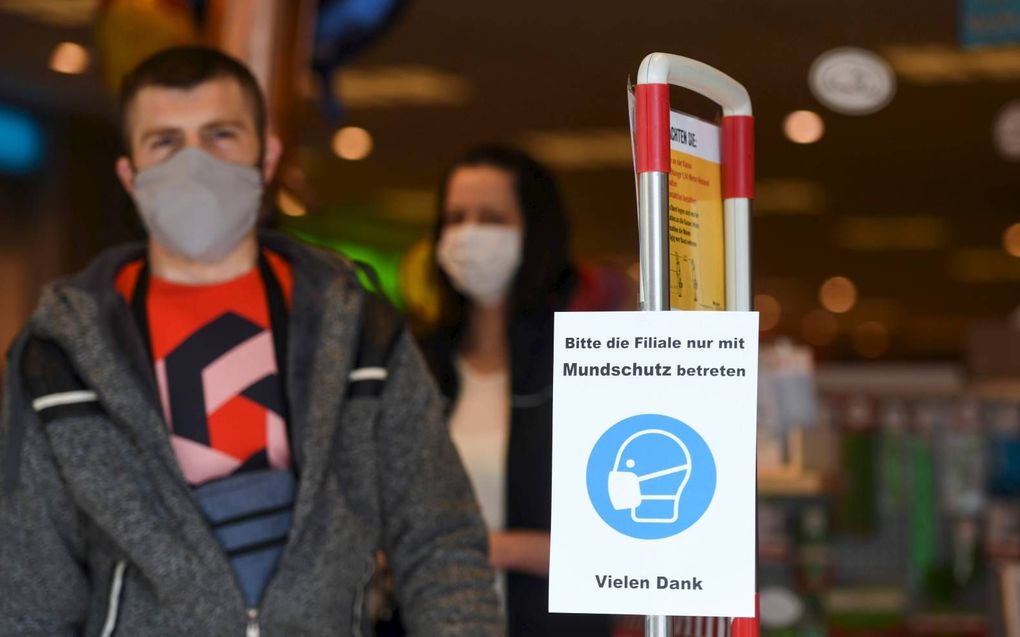 Bij de ingang van een winkel in de Duitse stad Hamm hangt een briefje met daarop de vraag om de winkel alleen met gezichtbescherming te betreden. beeld AFP, Ina Fassbender