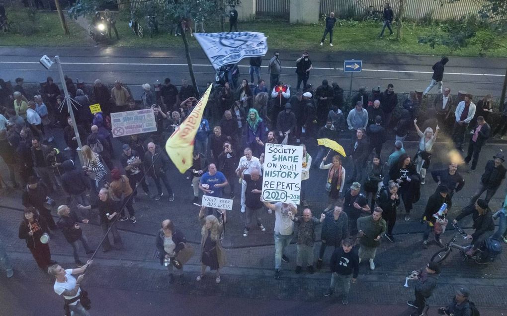 Demonstranten protesteren bij het ministerie van Justitie in Den Haag waar dinsdag de coronapersconferentie plaatsvond. Daarbij werd vuurwerk afgestoken. beeld ANP, Bart Maat