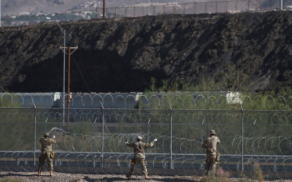 Medewerkers van de Texaanse grenswacht rollen prikkeldraad uit bij het grenshek tussen Mexico en Texas, bij Ciudad Juarez, 19 oktober. beeld EPA, Luis Torres