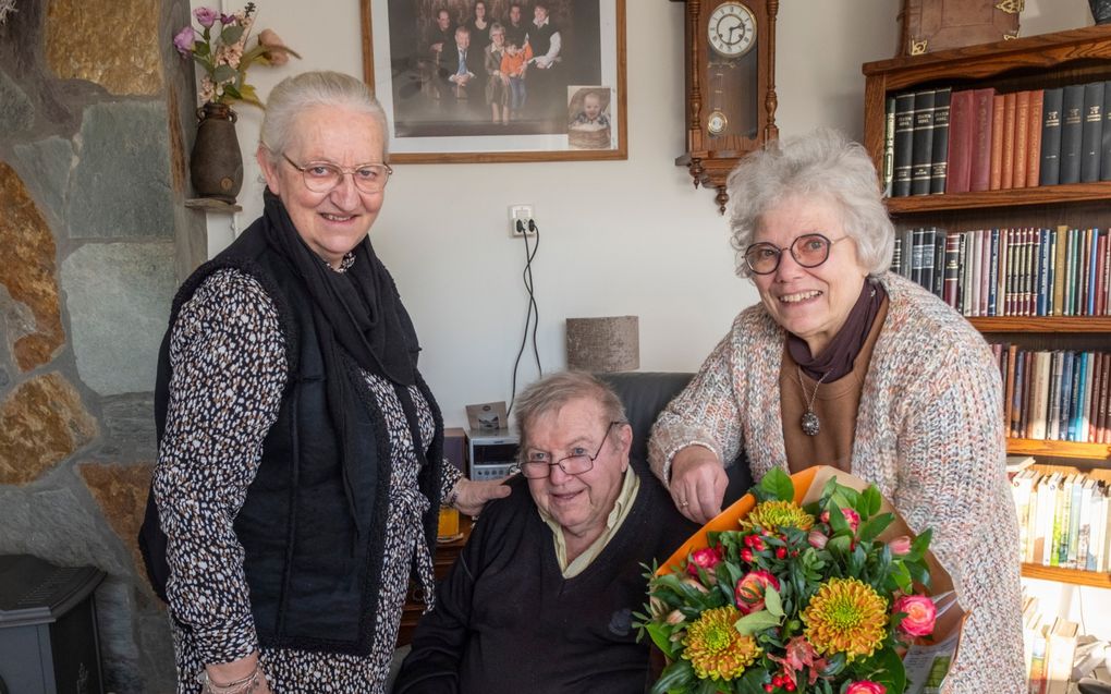 Trudie Aarnoutse (r.) ontvangt een bos bloemen van haar echtgenoot Aart en haar vriendin Magda Wagenaar (l.). „Trudie zorgt dagelijks en met alle liefde voor haar man.” beeld Dirk-Jan Gjeltema