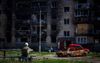 Burgers zitten gelaten voor een kapotgeschoten wooncomplex in Irpin. De oorlog in Oekraïne duurt nu honderd dagen. beeld AFP, Dimitar Dilkoff