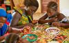 Filomena (r.) werkt samen met haar moeder met kraaltjes in het ontmoetingscentrum voor gehandicapte kinderen in Buba, Guinee-Bissau. Beeld Jaco Klamer