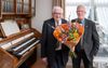 Evert Jan Huttinga (r.) geeft Henk Morren een bos bloemen. „We zijn al ruim vijftig jaar vrienden. Het is bijzonder dat we samen wekelijks het Evangelie bij ouderen brengen.” beeld Herman Stöver