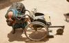 Gerda Klaver inspecteert een in onbruik geraakte rolstoel in het binnenland van Guinee-Bissau . Even later zou ze  hem in de laadbak van haar auto tillen en voor reparatie meenemen.