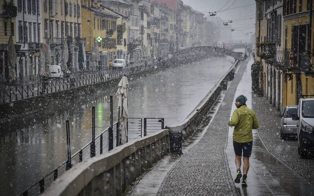 Een man met ijsmuts jogt door de straten van Milaan. Het sneeuwt licht in de Italiaanse stad.  beeld EPA, Matto Corner