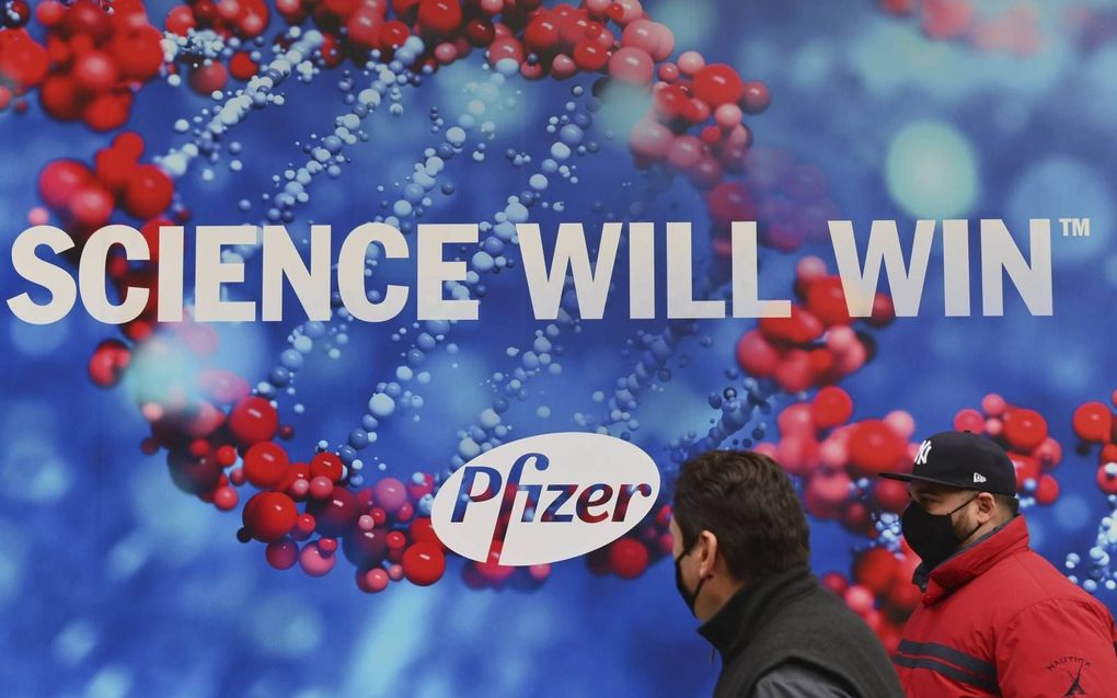 Mensen lopen voorbij het hoofdkantoor van farmaceut Pfizer in New York. De Engelse medicijnautoriteit MHRA adviseert zwangere vrouwen en allergiepatiënten het vaccin voorlopig niet te nemen. beeld AFP, Angela Weiss