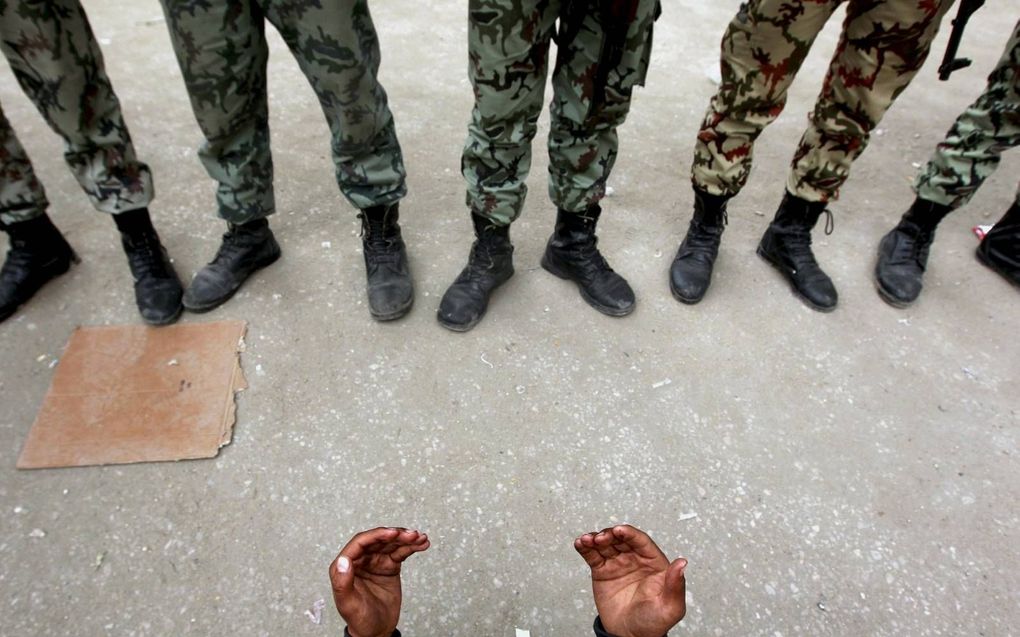 Een Egyptische demonstrant bidt pal voor gewapende militairen, vlakbij het Tahrirplein in Caïro in februari 2011.  beeld Reuters, Yannis Behrakis