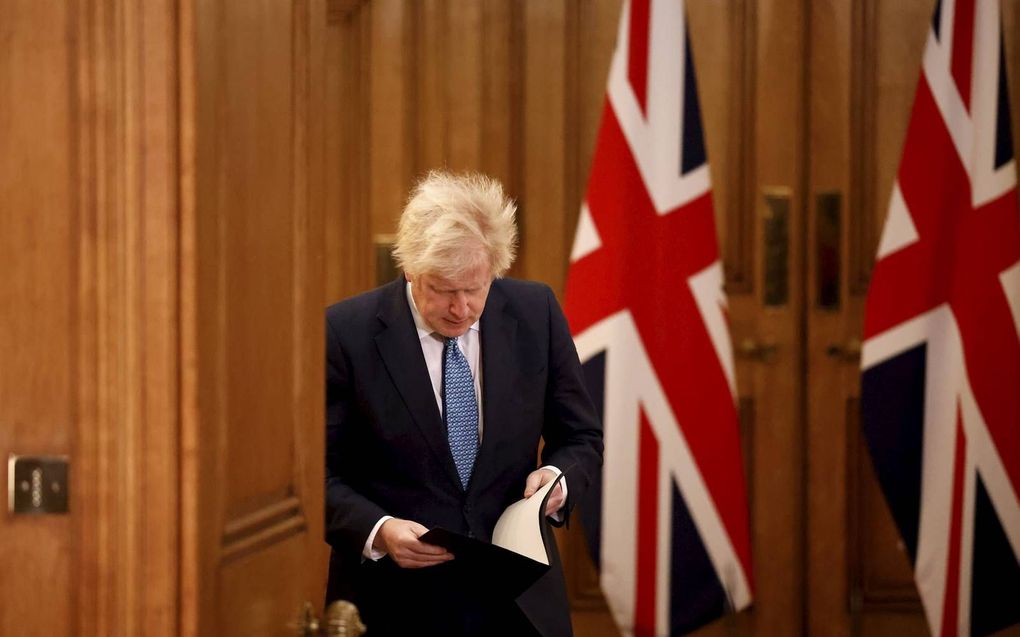 De Britse premier Boris Johnson kijkt maandag nog wat papieren na voordat hij een persconferentie geeft in Londen. beeld AFP, Tolga Akmen