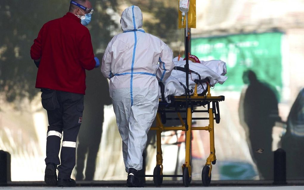 Gezondheidswerkers rijden een patiënt naar het Bellvitgeziekenhuis in Barcelona, Spanje. De druk op de ziekenhuizen is hoog. beeld EPA, Alejandro Garca