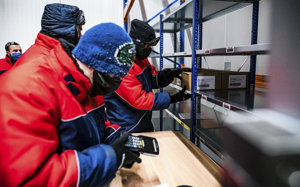 Medewerkers van de logistieke farmareus Movianto in Oss verwerken een levering van het Modernavaccin. Deze week kunnen onder meer huisartsen dit vaccin krijgen. beeld ANP, Rob Engelaar