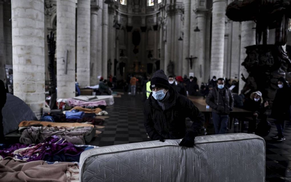 Enkele honderden migranten zonder verblijfsvergunning bezetten sinds zondag de Brusselse Begijnhofkerk. Ze vragen daarmee toegang tot gezondheidszorg en recht op werk. Volgens de Vlaamse krant De Standaard hebben de migranten „gedeeltelijke toestemming” van priester Daniël voor hun actie, „zolang die coronaproof blijft.” beeld AFP, Kenzo Tribouillard