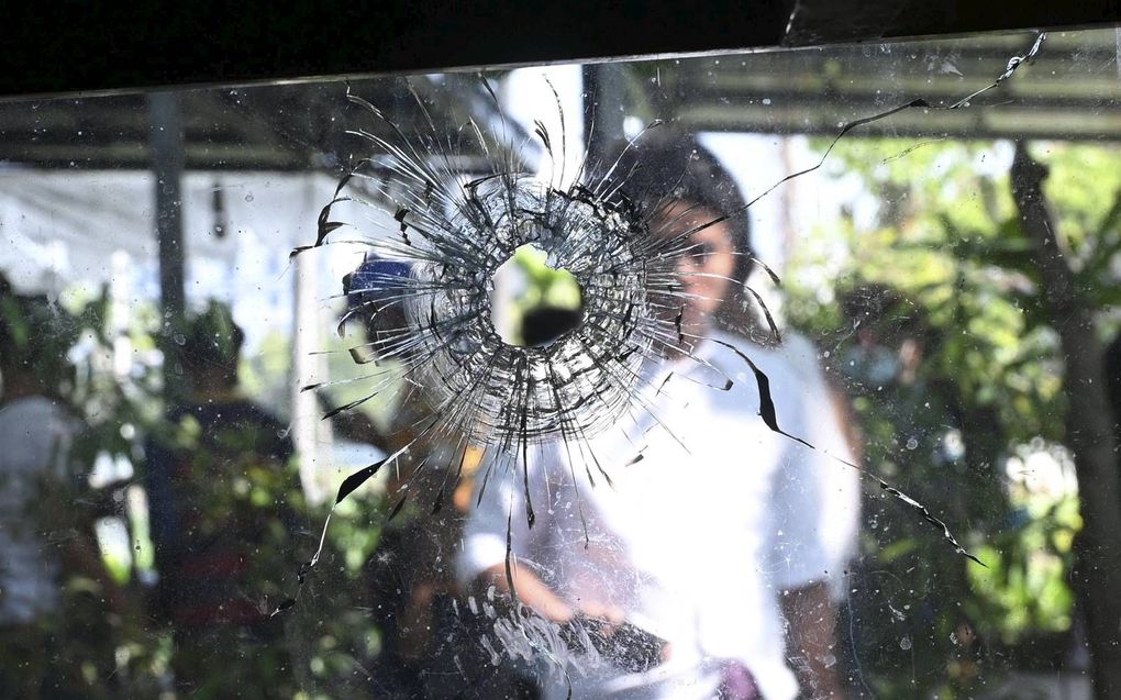 De ochtend na de schoten. Een vrouw is onder de indruk van het gat in de ruit nadat het leger van Myanmar woensdag schoten loste op betogers in het centrum van de hoofdstad Yangon.  beeld AFP