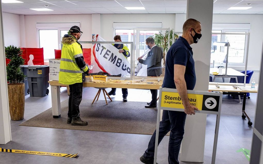 Burgemeester Bram van Hemmen (in pak) helpt in Maasdam mee met het inrichten van een stembureau. beeld Dirk Hol