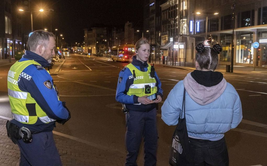 De handhavers Addie Schrijvershof en Evita de Kruijff spreken in de Utrechtse binnenstad een jongedame aan. Tegen de avondklokregels in is ze na 21.00 uur nog op straat.  beeld Erik Kottier