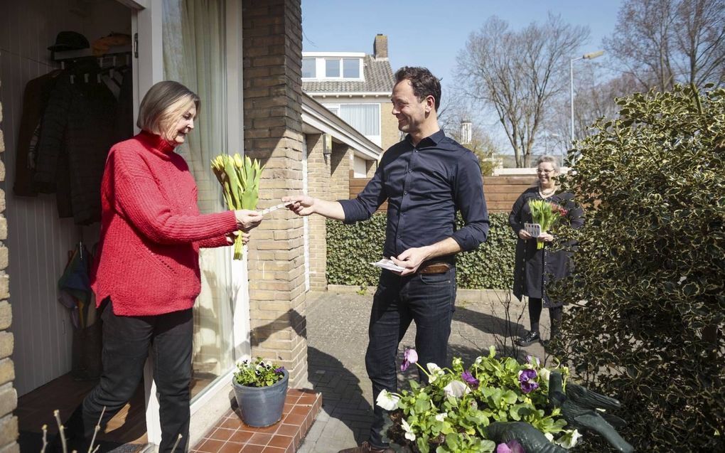 Veldwerker Jan Geerts (r.) gaat in Alkmaar bij de buren langs met een kaart met Bijbeltekst en een bosje tulpen. beeld Eran Oppenheimer