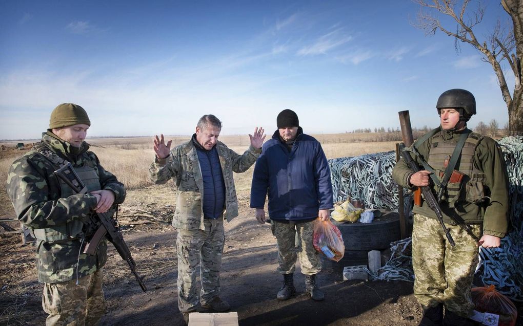 Voorganger Gennadiy Mochnenko (m.) bidt op het hoogtepunt van de oorlog in Oost-Oekraïne in 2015 met Oekraïense soldaten aan het front. beeld RD, Henk Visscher