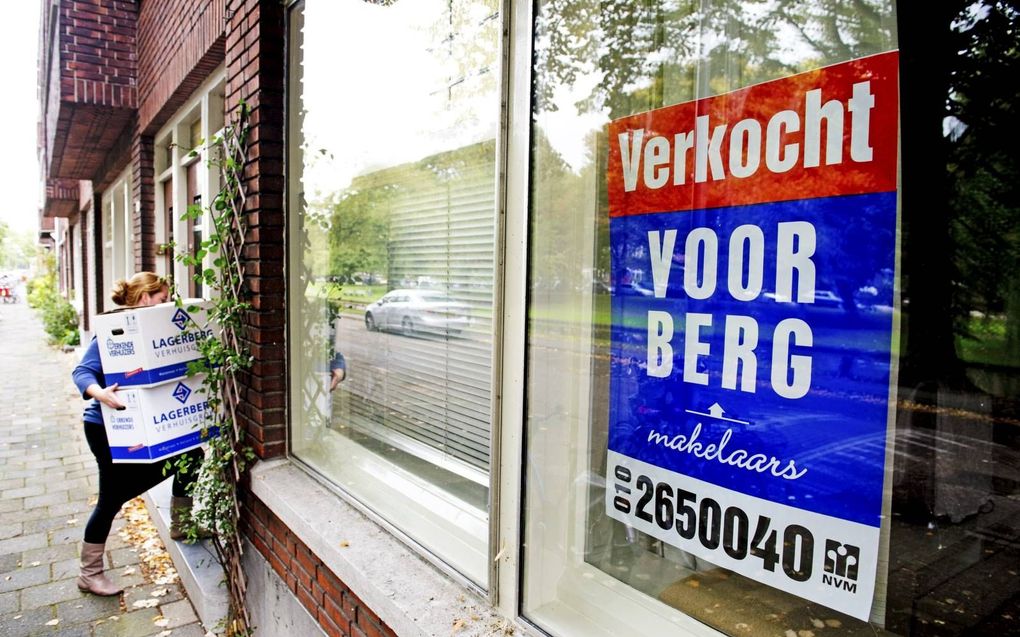 Een vrouw draagt verhuisdozen een pas verkocht huis in. De strenge inkomensnormen voor jongeren om een hypotheek te krijgen, maakt het voor hen lastig om hun eerste huis te kopen. beeld ANP, Robin Utrecht