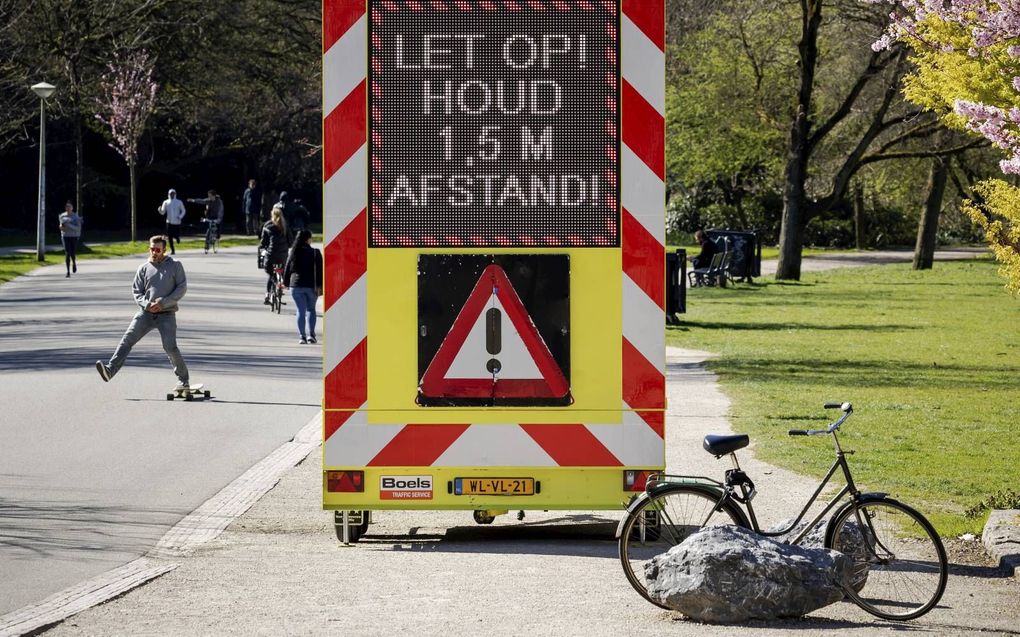 Een bord wijst bezoekers van het Vondelpark erop dat ze 1,5 meter afstand moeten houden om de verspreiding van het coronavirus tegen te gaan. beeld ANP, Robin van Lonkhuijsen