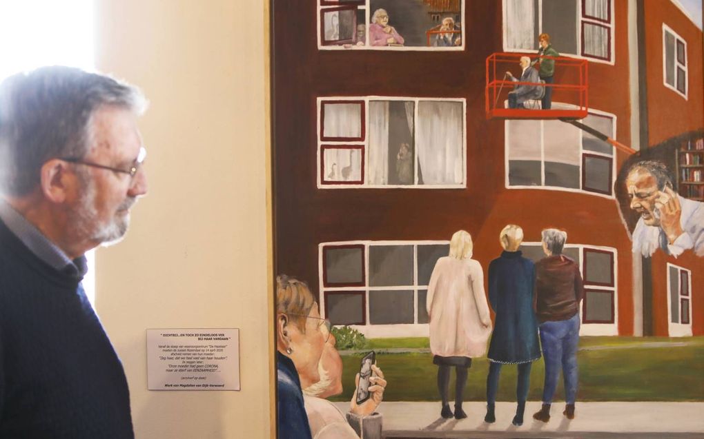 Co Mateboer bij het schilderij dat Magdalien van Dijk-Verwoerd maakte over corona. De expositie in het oude stadhuis van Genemuiden omvat twintig kunstwerken. beeld Vidi­Photo