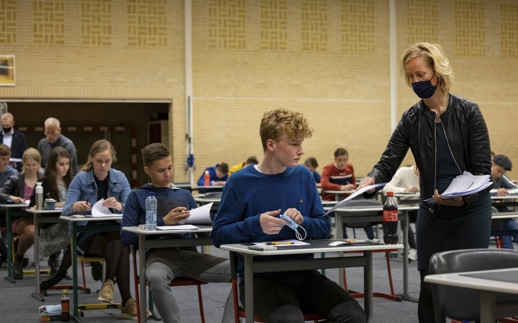 Klaar voor de start. Een docent deelt de eerste examens bedrijfseconomie uit aan havoscholieren op de Pieter Zandt scholengemeenschap in Kampen. beeld Freddy Schinkel