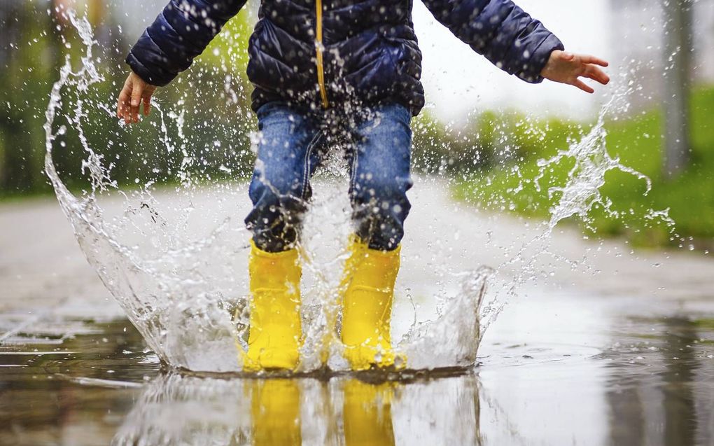 Veel regen heeft voor kinderen ook zijn leuke kanten: lekker in de plassen stampen.  beeld iStock