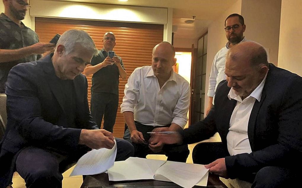 De hoofdrolspelers in de nieuwe Israëlische regering, woensdagavond bij de ondertekening van het coalitieakkoord (zittend v.l.n.r.): Yair Lapid, Naftali Bennett en Mansour Abbas. beeld AFP, Ra’am